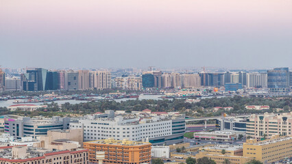 Deira modern and old buildings canal aerial view of Dubai Creek day to night timelapse.