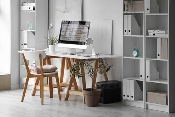 Interior of stylish office with programmer's workplace and shelf units