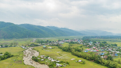 Fototapeta na wymiar Rice field aerial shot at north east of India. Aerial views of beautiful mountain small house and rice terraces field at kangpokpi village rice terraces with senapati river manipur india.