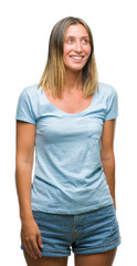 Fototapeta premium Young beautiful woman over isolated background looking away to side with smile on face, natural expression. Laughing confident.