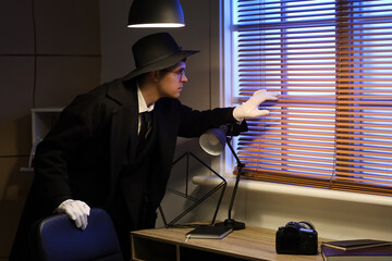 Male spy looking out window in office at night