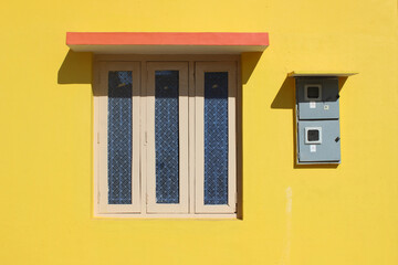  Sunny yellow wall with window, featuring chajja, providing a bright and inviting facade also creating a warm and welcoming exterior.