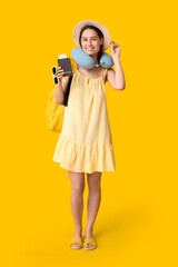 Fototapeta premium Young happy woman in hat with passport and backpack on yellow background. Travel concept