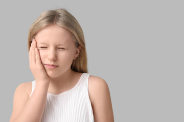 Young girl suffering from toothache on grey background