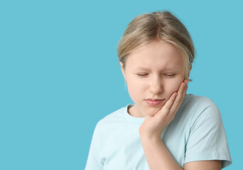 Young girl suffering from toothache on blue background