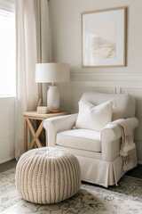 A modern farmhouse style reading nook with an oversized beige linen chair, plush knit ottoman and a wooden side table featuring a ceramic lamp. A room is bathed in soft natural light from large window