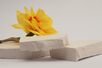 White Stones platform podium, Yelow flower on beige light background. Minimal empty display product presentation scene.