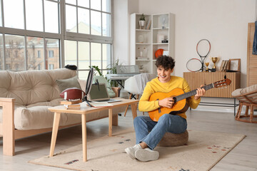 Male student playing guitar while streaming at home