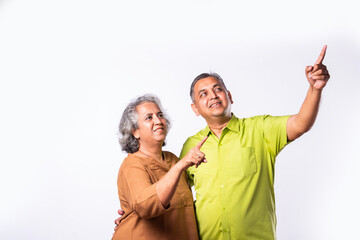 Asian indian mid age couple with grey hair pointing or presenting on white background
