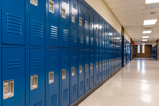 Empty school hallway with blue metal student lockers	