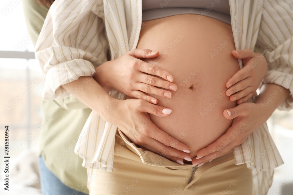 Canvas Prints Young pregnant woman with her wife touching belly at home, closeup