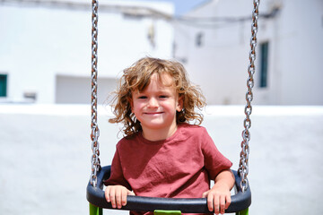 Portrait of a little boy having fun on a swing on the playground.