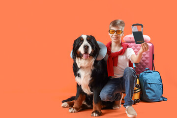 Little boy with passport and Bernese mountain dog on orange background. Travel concept