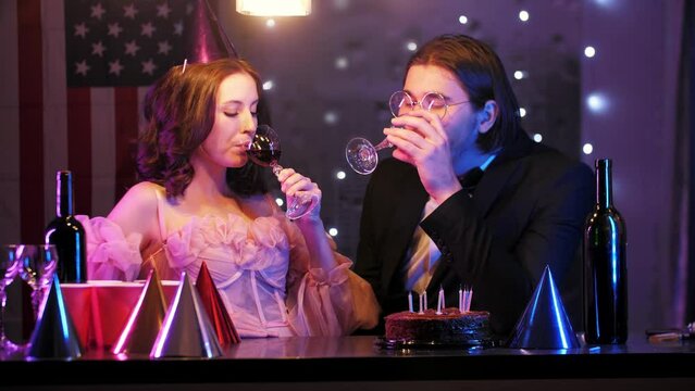 The birthday girl and her boyfriend enjoy a glass of red wine after a successful birthday party. They share a sweet kiss on the lips. Mid shot. 4k