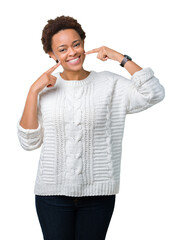 Beautiful young african american woman wearing sweater over isolated background smiling confident showing and pointing with fingers teeth and mouth. Health concept.