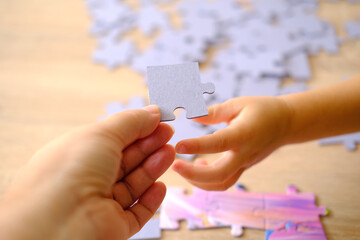 little child and mom playing together, parent teaches daughter to assemble puzzles, cognitive...