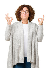 Beautiful middle ager senior woman wearing jacket and glasses over isolated background relax and smiling with eyes closed doing meditation gesture with fingers. Yoga concept.
