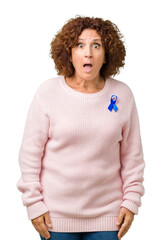 Middle ager senior woman wearing changeable blue color ribbon awareness over isolated background...