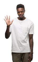 Young african american man wearing white t-shirt showing and pointing up with fingers number five while smiling confident and happy.