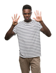 Young african american man wearing glasses and navy t-shirt showing and pointing up with fingers number nine while smiling confident and happy.