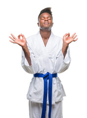 Young african american man over isolated background wearing kimono relax and smiling with eyes closed doing meditation gesture with fingers. Yoga concept.