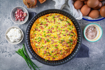 Homemade oven baked frittata with curd cheese, bacon, onion and chives
