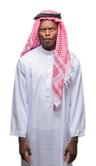 Young arabic african man wearing traditional keffiyeh over isolated background making fish face...