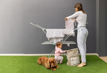 A woman hangs clothes on a clothesline while her daughter looks into the laundry basket