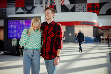 Cheerful hipster travelers are hugging at train station.