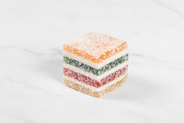 Multi-layered multicolored jelly marmalade of square shape. White background. Close-up