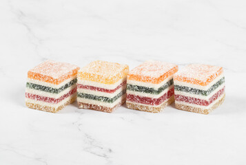 Vegan Multi-layered multicolored jelly marmalade of square shape. White background. Close-up - obrazy, fototapety, plakaty