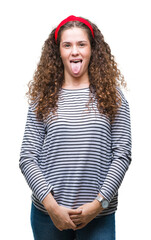 Beautiful brunette curly hair young girl wearing stripes sweater over isolated background sticking tongue out happy with funny expression. Emotion concept.