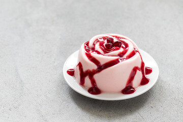 Vegan Pomegranate cream dessert, Panna Cotta in the shape of a rose. With pomegranate sauce. On a plate. Copy space