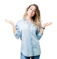 Beautiful young blonde woman over isolated background clueless and confused expression with arms...