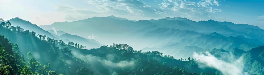 A breathtaking landscape of mountains enveloped in mist with lush greenery - obrazy, fototapety, plakaty