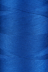 Texture of blue color threads in spool close up, macro. Sewing threads bobbin abstract background,...