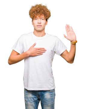Young handsome man with afro hair wearing casual white t-shirt Swearing with hand on chest and open palm, making a loyalty promise oath