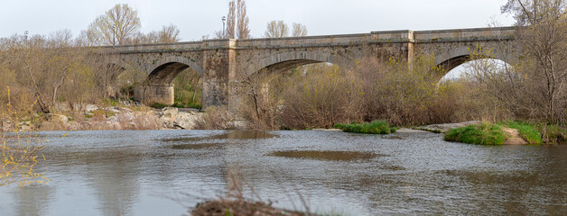 Medieval bridge with the Tormes river in Guijuelo, Salamanca, Spain - obrazy, fototapety, plakaty