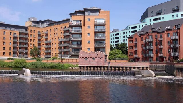 Footage of a beautiful waterfall located in the built up area of the Leeds City Centre known as The Leeds Dock on a bright sunny summers day showing the waterfall from the River Air
