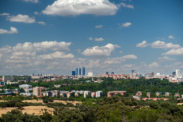 A city view with a tall building in the background. The sky is blue with some clouds. The city is...