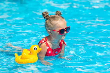 Little girl having fun on vacation at the hotel pool. Colorful vacation concept. Summer outdoor...