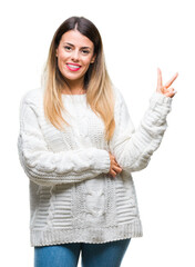 Young beautiful woman casual white sweater over isolated background smiling with happy face winking...