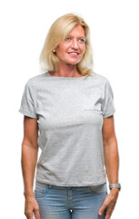 Fototapeta premium Middle age blonde woman over isolated background looking away to side with smile on face, natural expression. Laughing confident.