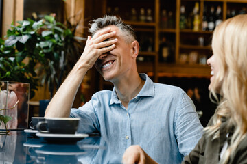 Facepalm emotion. Laughing smiling mature caucasian man husband talking with his wife woman on a...