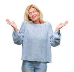 Middle age blonde woman wearing winter sweater over isolated background clueless and confused...