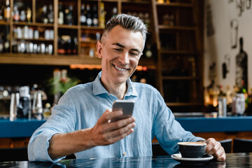 Smiling confident caucasian mature businessman freelancer boss using cellphone for surfing net,...