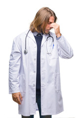 Young handsome doctor man with long hair over isolated background tired rubbing nose and eyes feeling fatigue and headache. Stress and frustration concept.