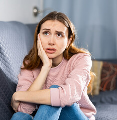 Upset woman crying while sitting on a sofa in a room