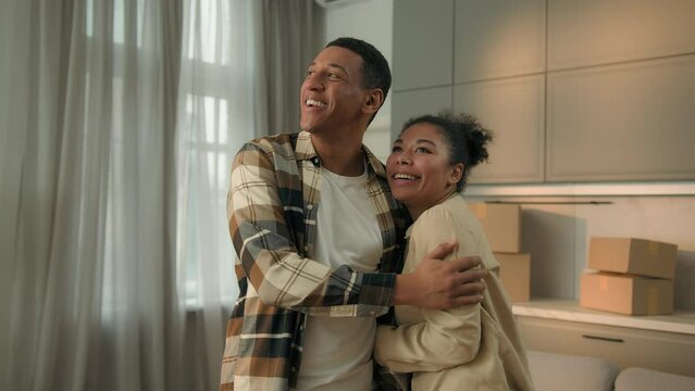 Happy excited couple African American family home owners moving in new apartment buying house real estate mortgage relocation renovation smiling woman man affection hug buy rent flat investment credit