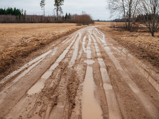Dirty muddy country road with deep car truck full with water and clay. Transportation in a county...